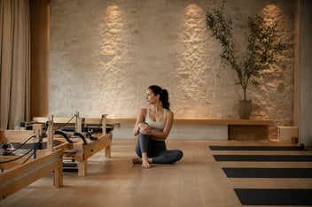 Estudio de Pilates con camilla reformer de madera y colchonetas en el suelo